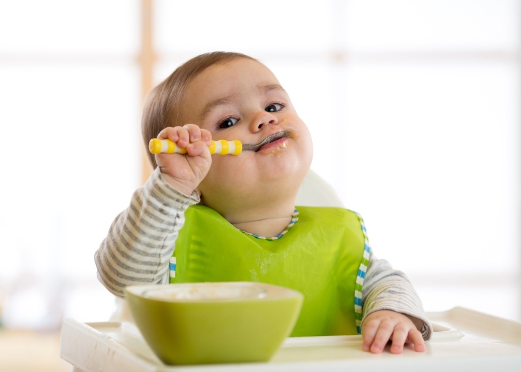 Baby zufüttern-Baby mit Löffel im Mund 