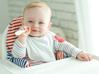 Baby zufüttern-Lachendes Baby mit Löffel